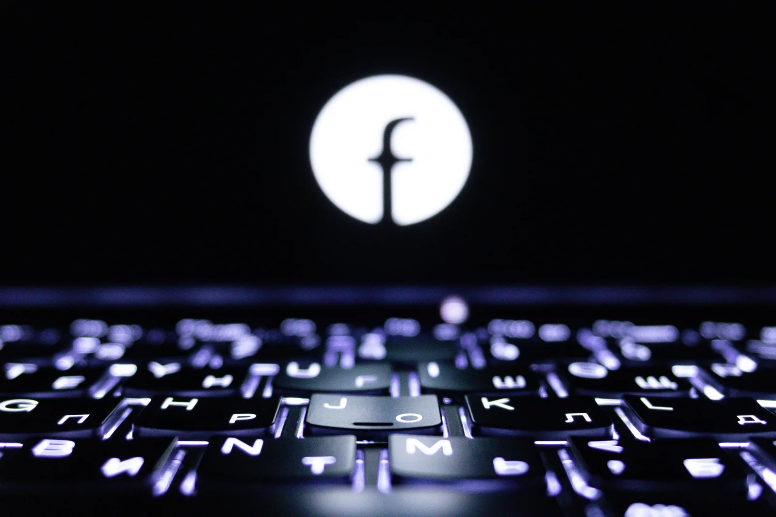 Glowing Facebook logo above a backlit laptop keyboard (photo: Pexels, https://www.pexels.com/photo/illuminated-keyboard-with-symbol-in-focus-33427651/)
