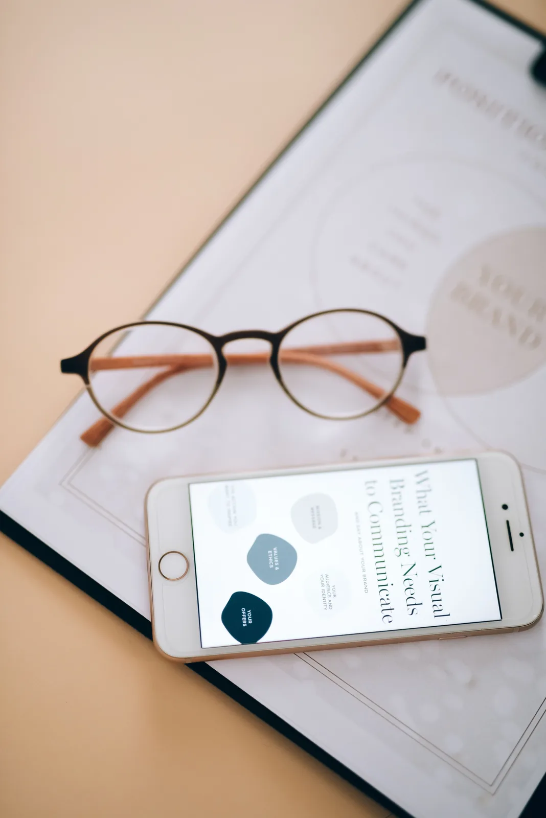 Widok z góry na smartfon i okulary leżące na biurku (photo: Pexels, https://www.pexels.com/photo/top-view-of-a-smartphone-and-eyeglasses-8970672/)