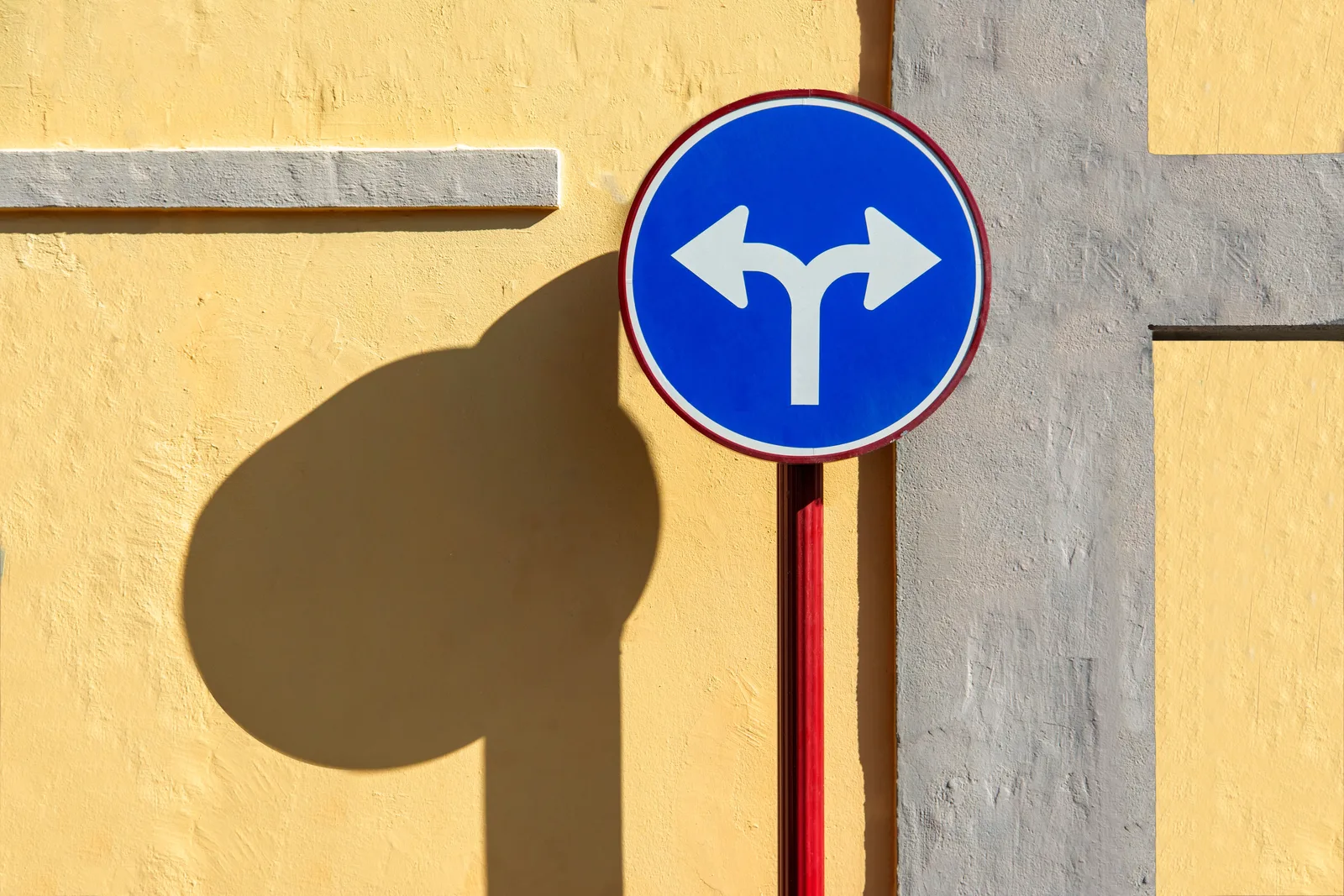 Blue street sign casting a sharp shadow on a bright yellow wall (photo: Pexels, https://www.pexels.com/photo/street-sign-with-shadow-on-yellow-wall-30974520/)