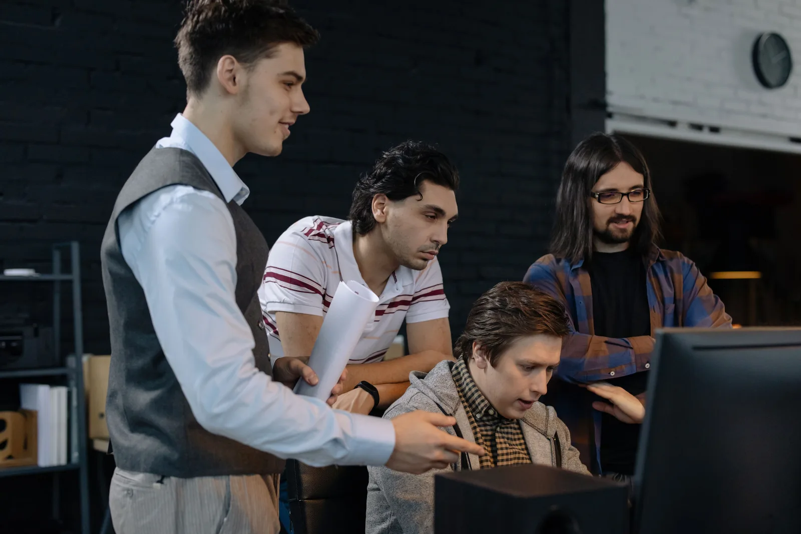 Team of employees discussing a project while standing over a colleague working at a computer (photo: Pexels, https://www.pexels.com/photo/employees-discussing-project-standing-over-programmer-working-at-a-computer-6804079/)
